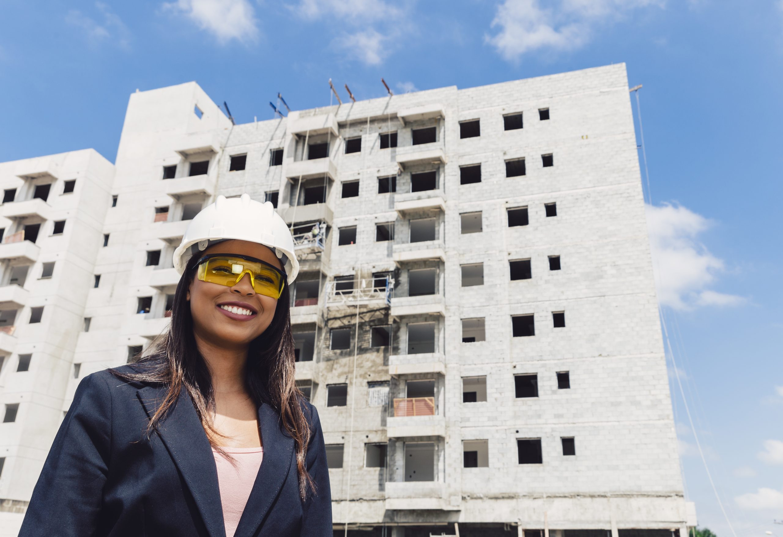 Happy construction lady wearing an helmet at a construction site